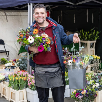 Trader with flowers standing by a flower stall